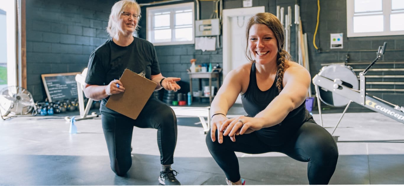 Workout session with woman doing sit-ups and coach assisting