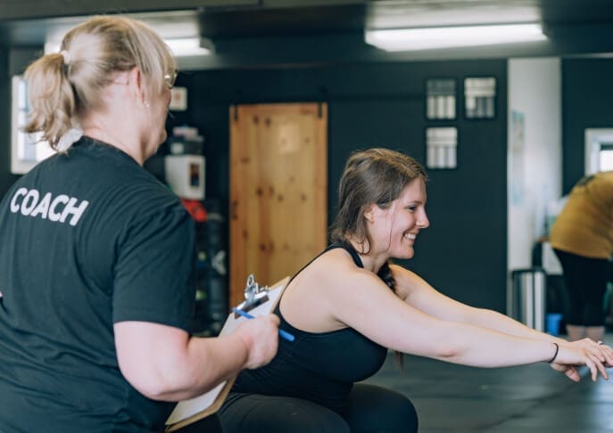 Focused woman exercising under the supervision of a trainer